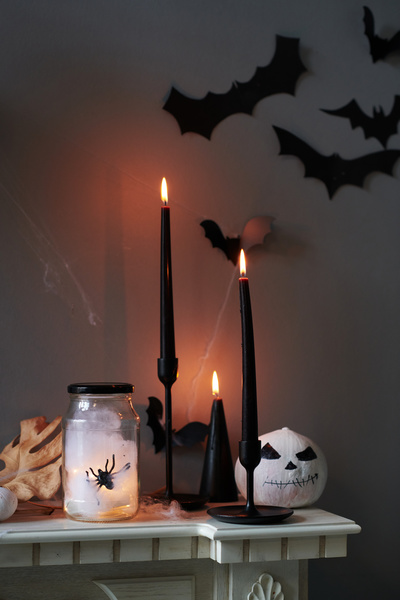 Can with Spider Stands next to Lit Halloween Candles